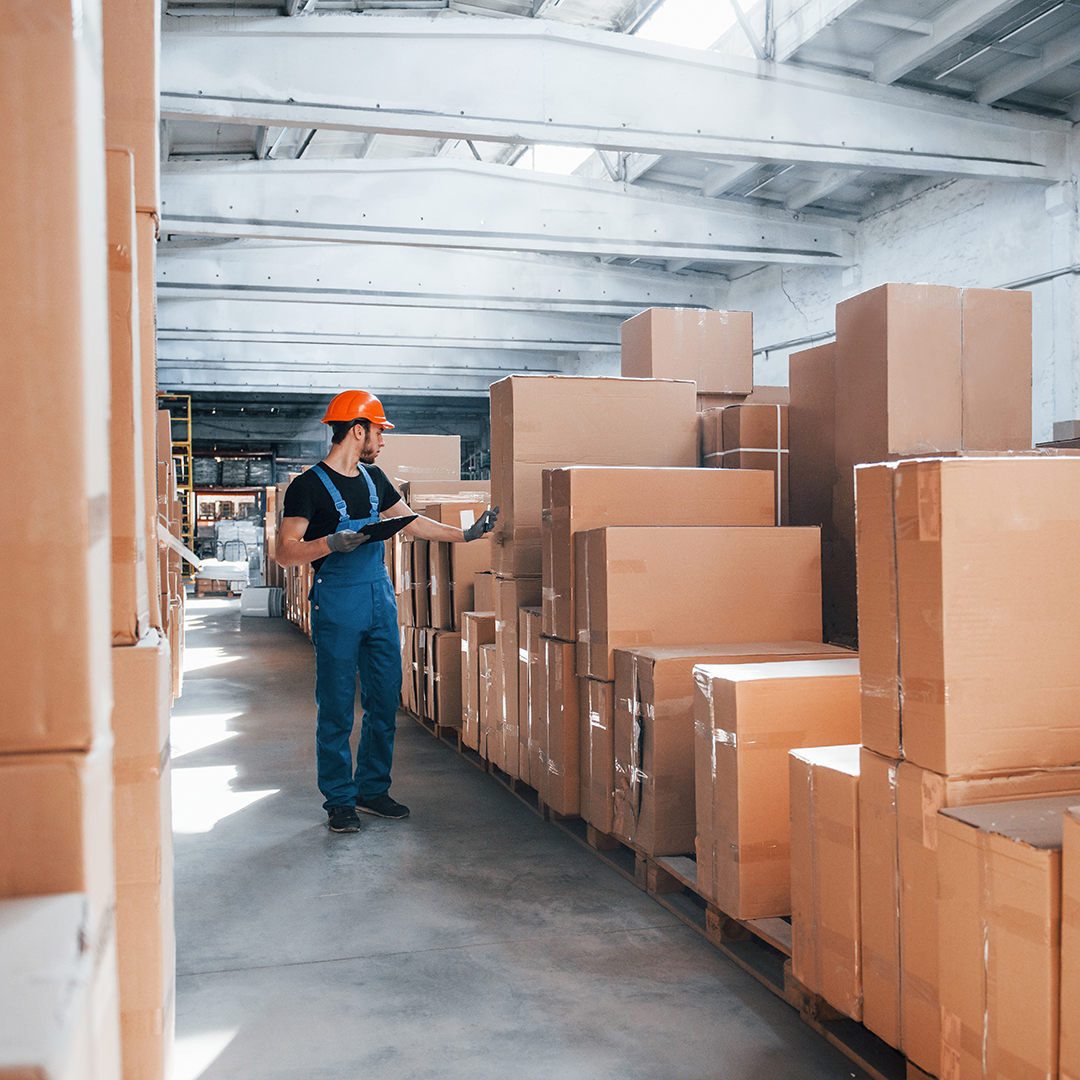 Storage worker in uniform and notepad in hands checks production